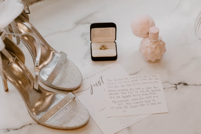 Wedding vows, ring, and gold heels on marble