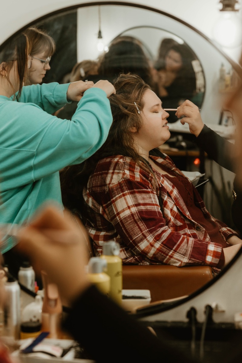 Bride getting hair and makeup done in a warm salon